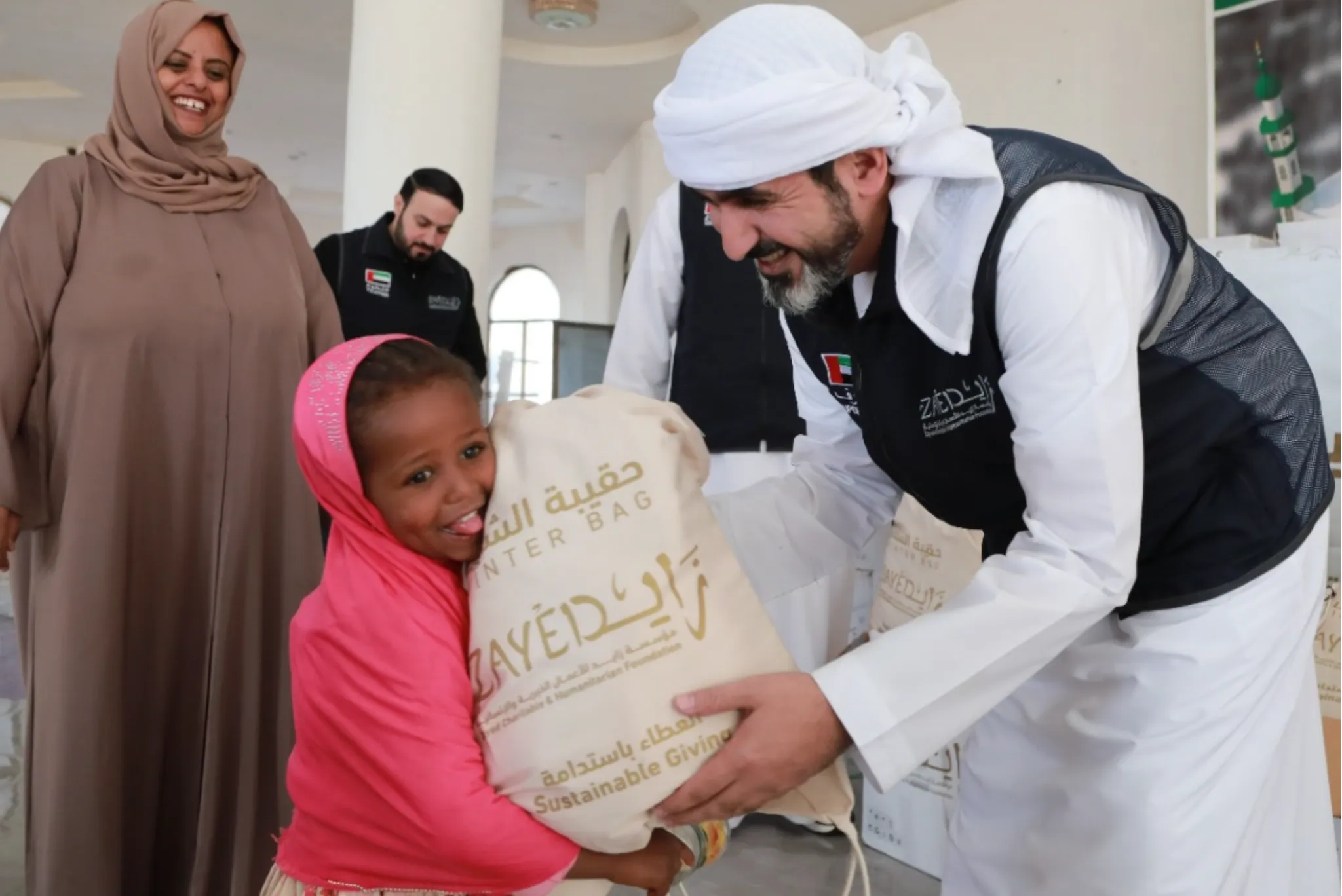 UAE Aid and Zayed Charitable and Humanitarian Foundation volunteer distributes a winter bag to a young girl 